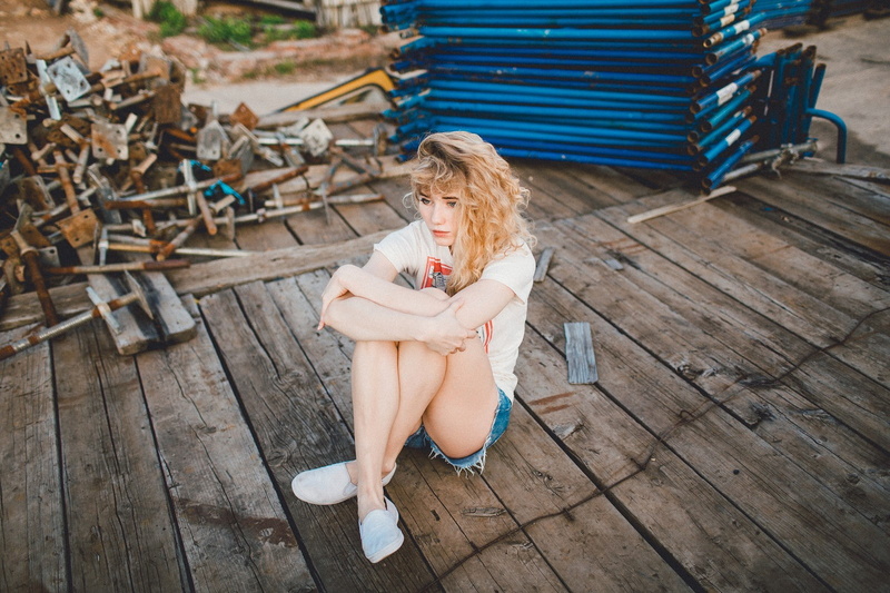 hairstyle, seat, one person, wood, beautiful woman, full length, sitting, legs, wavy hair, women, fashion, looking away, lifestyles, blond hair, outdoors