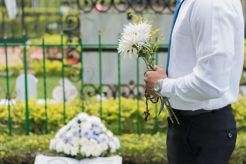 flowers, park, real people, flowering plant, outdoors, people, focus on foreground, midsection, cemetery, vulnerability, lifestyles, peace, plant, man