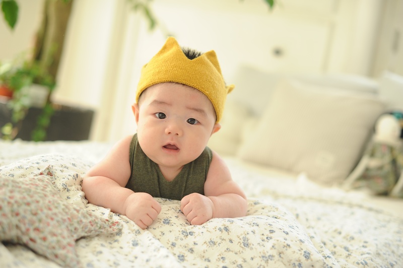 baby, furniture, lying down, portrait, indoors, one, baby clothing, innocence, babyhood, happy, smile, bed, lying on front, focus on foreground, young
