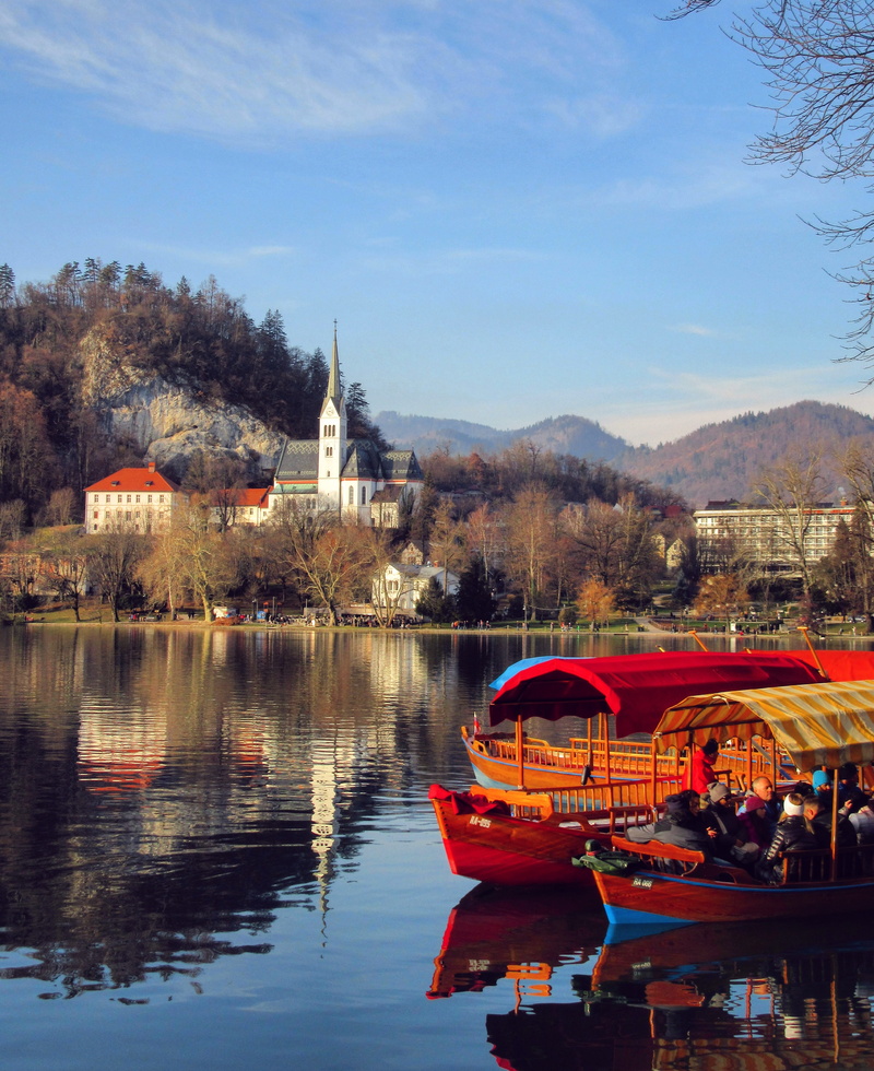 architecture, nautical vessel, plant, bled, sunrise, no people, building exterior, mountain, sky, water, reflection, boat, beauty in nature, moored, mode of transportation