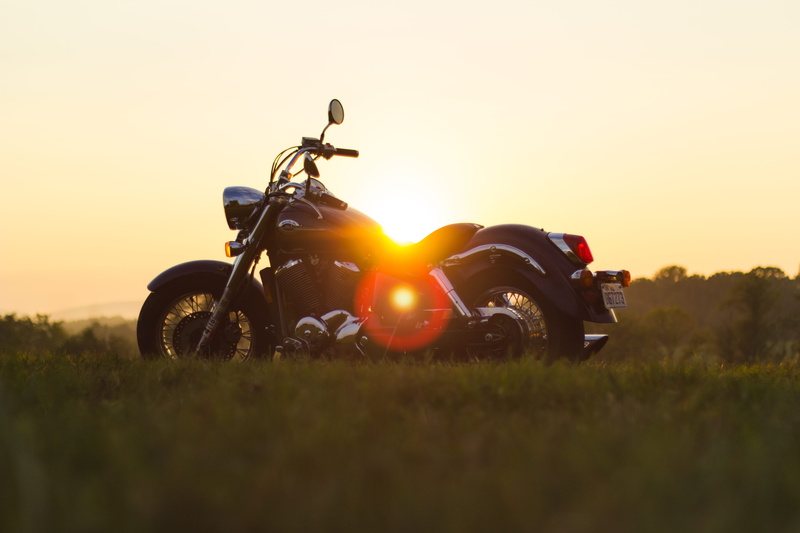 motorcycle, lens flare, grass, motorbike, grassfield, parked, outdoors, nature, copy space, plant, sunset, sky, cruiser, trip, daylight, transportation