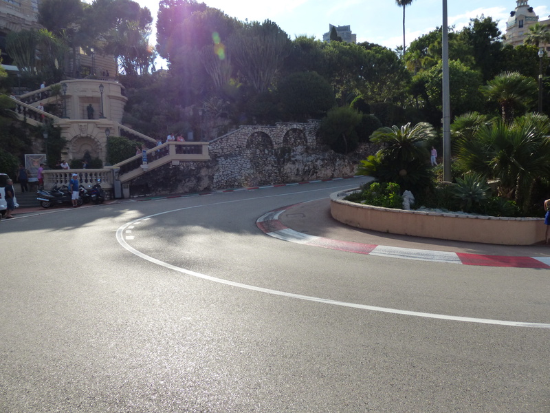 city, symbol, transportation, daytime, monte carlo, direction, plants, nature, road, built structure, monaco, curve, formula 1, uphill, concrete, no people