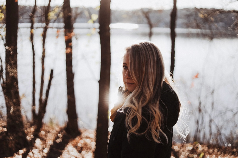 sunlight, one person, black, clothing, 4K, lifestyles, warm clothing, tree, standing, water, leisure activity, united states, woman, trunk, long hair