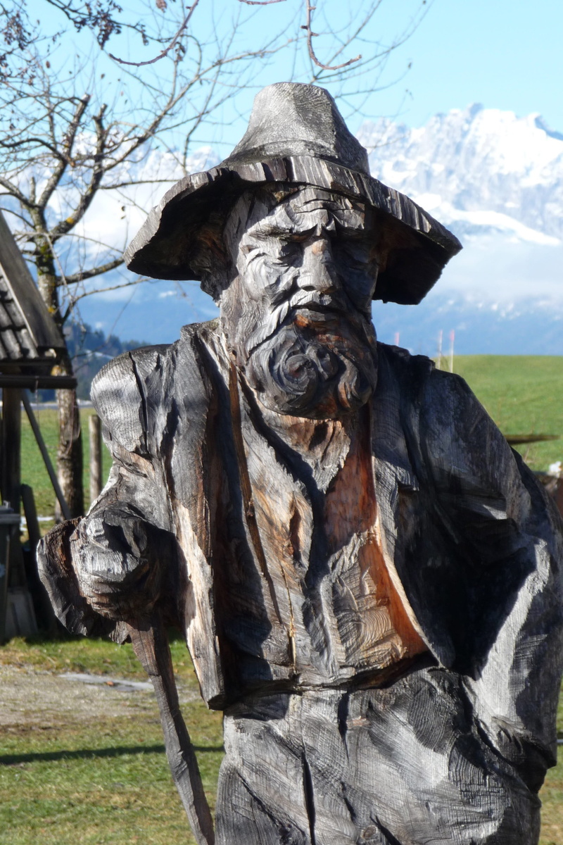 grass, outdoors, 2K, art and craft, nature, man, wood carving figurine, gardena, Figurine, field, wood, sunlight, mountains, craft, statue, plant, tree
