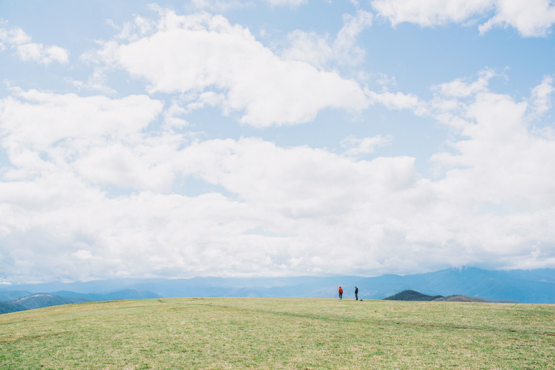 view, men, mountain, scenics, field, day, non-urban scene, standing, outdoors, environment, blue, incidental people, two, landscape, daytime, highland