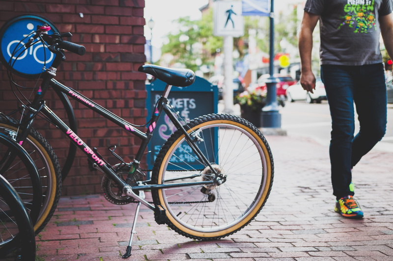 potted plant, black, pottery, street, transportation, vehicle, commuter, brick, outdoors, footpath, sidewalk, land vehicle, one person, canada, human, focus on foreground