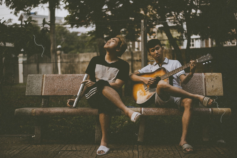 lifestyles, playing, front view, plucking an instrument, beside, artist, people, musical instrument, togetherness, another, young adult, men, friendship