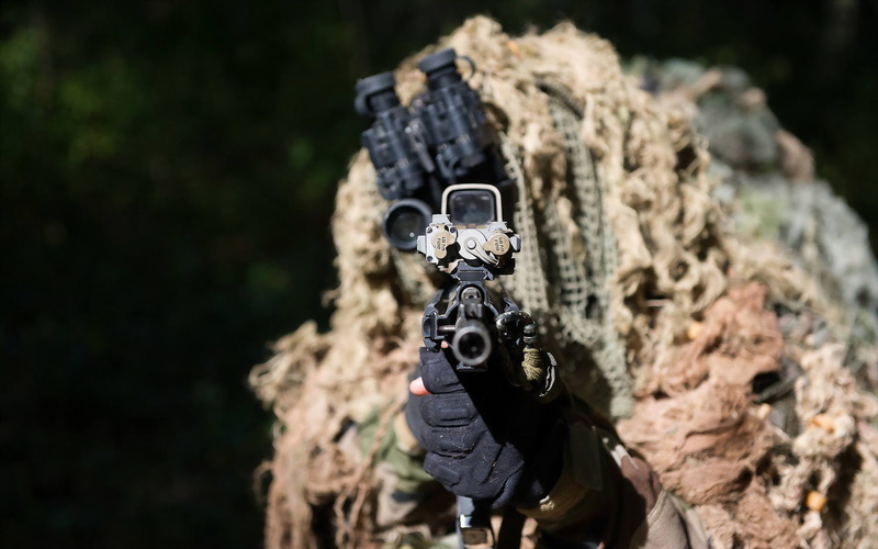 rifle, one person, photographer, focus on foreground, soldiers, land, rock - object, camera - photographic equipment, holding, outdoors, digital camera