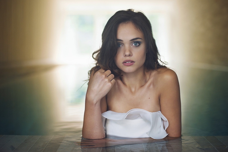 focus on foreground, beautiful woman, sitting, brown hair, adult, wet body, long hair, women, white tops, swimming pool, hairstyle, day, front view, contemplation