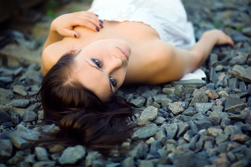 one person, hair, lying down, 1080P, selective focus, women outdoors, looking away, hairstyle, sadness, pebble, relaxation, rock, looking at camera, women