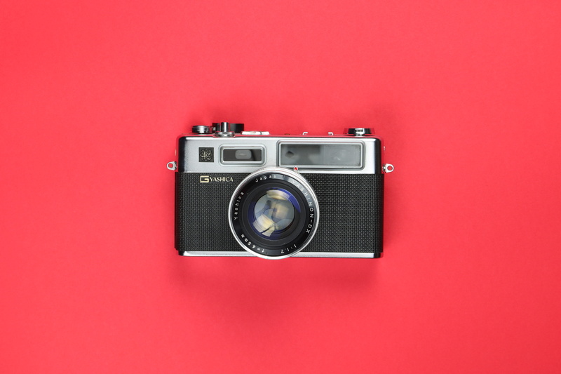 strap, video camera, machine, symbol, red background, photography themes, close-up, point, nostalgia, indoors, electronics, couch, camera, simplicity, page