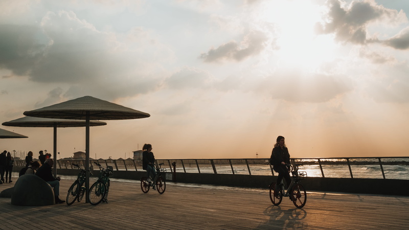 water, adult, sun, cycling, real people, women, bridge - man made structure, nature, cloud - sky, tel aviv port, sky, leisure activity, transportation