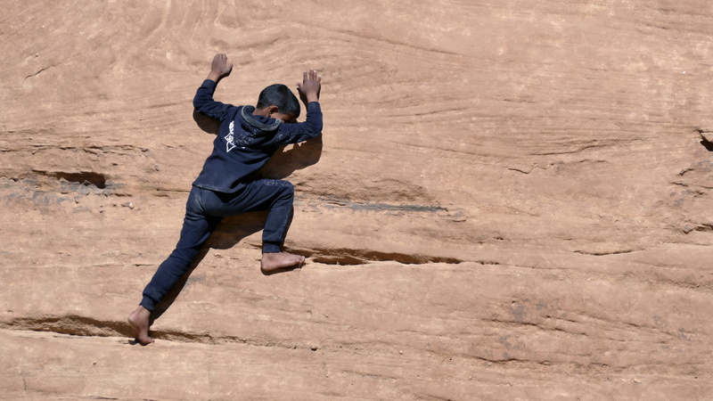 full length, climbing, solid, mid-air, agaba, desert, leisure activity, casual clothing, males, rock - object, sand, jordan, rocks, real people, human limb