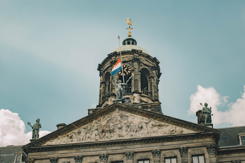 day, clouds, spire, clock tower, history, person, statue, city, built structure, the royal palace amsterdam, metropolis, nature, government, building, netherlands