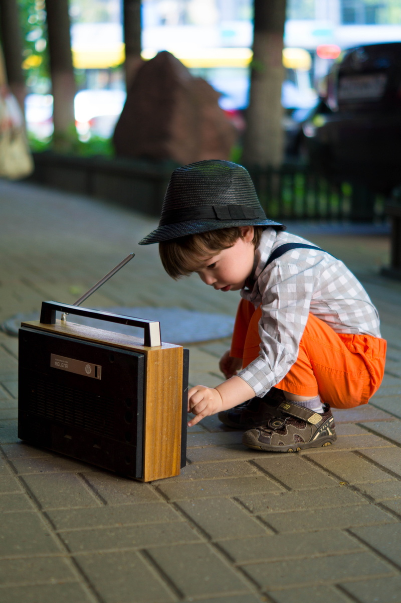 innocence, music, boys, radio, transistor, tuning, kid, day, side view, lifestyles, leisure activity, childhood, sitting, urban, blurred background, casual clothing