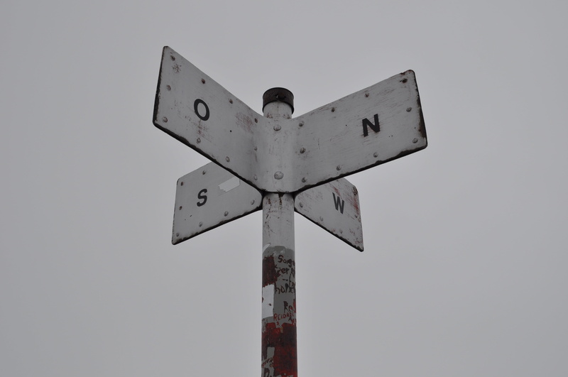 no people, direction, metal, rusty, fog, street, railroad crossing, compass point, directional sign, white color, sign, crossing sign, guidance, nature