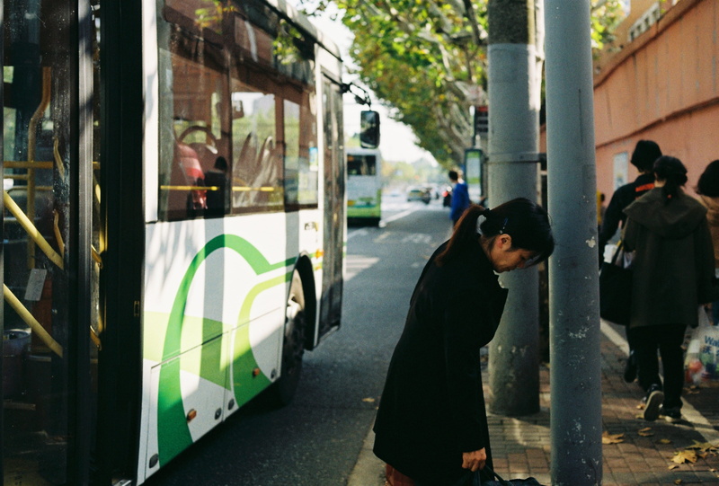 double decker bus, wheel, shoe, architecture, side view, school bus, vehicle, land vehicle, asphalt, footwear, transportation, person, outdoors, day, incidental people