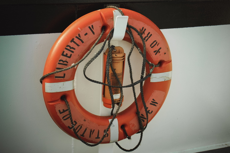 western script, life, circle, text, sign, no people, orange color, orage, hanging, indoors, wall - building feature, life belt, safety, geometric shape
