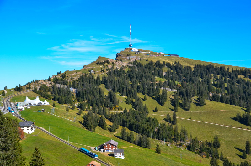 place of worship, mountain railway, distant view, mountain, blue, forest, beauty in nature, plant, alpine, green color, rigi kulm, day, no people, building exterior