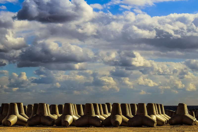 outdoors, in a row, tranquil scene, travel destinations, wave breakers, barrier, concrete, cloud - sky, side by side, abundance, sunlight, clouds, tetrapod