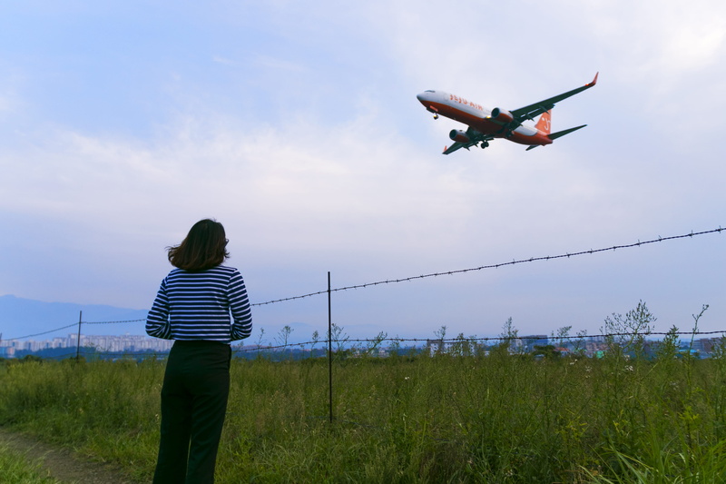 human arm, one person, lifestyles, hairstyle, aviation, sky, outdoors, flying, striped, nature, mid-air, leisure activity, women, air vehicle, airplane