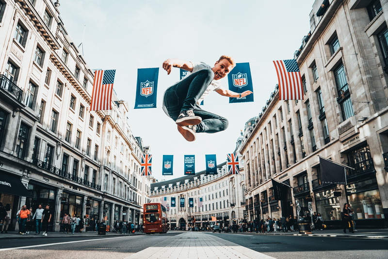 human arm, 5K, bunting, man, architecture, street, surface, streetscene, built structure, nfl, low angle view, cloudy, city life, concrete, one person