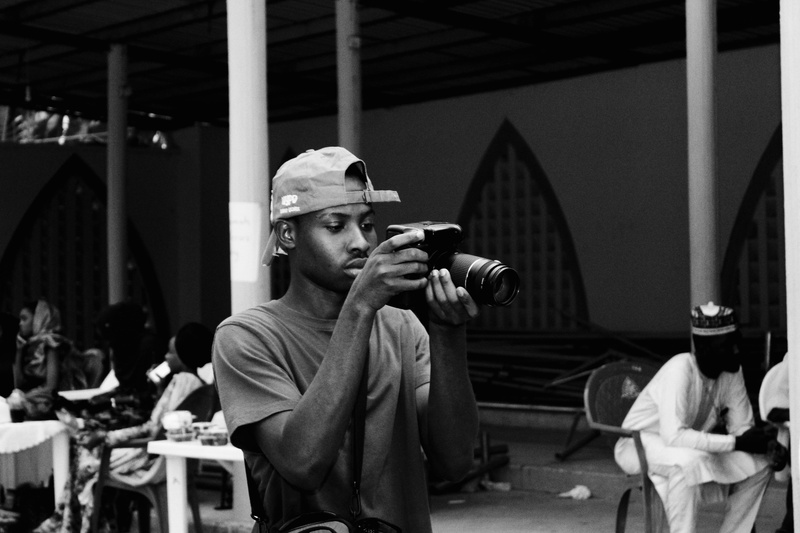 black and white, front view, cap, dslr, young adult, incidental people, apparel, activity, holding, camera, mahmoud, lifestyles, retrospective, nigeria