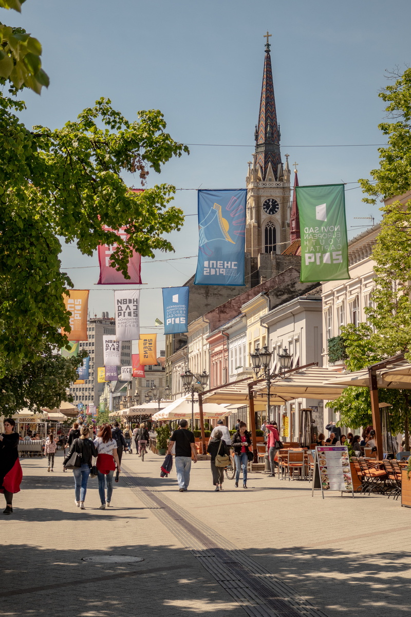 outdoors, group of people, path, town, pedestrian, building, urban, belief, sign, place of worship, building exterior, tree, real people, spire, human