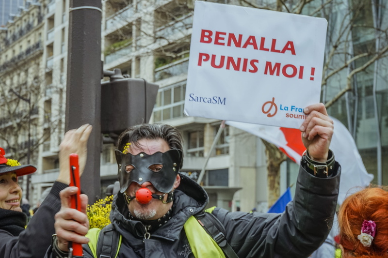 skin, near, sign, clown, performer, rallying, 4K, day, jacket, building exterior, clothing, protestor, holding, hat, headshot, focus on foreground, western script