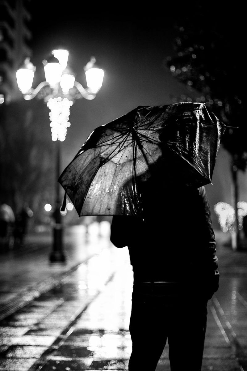 one person, night, black-and-white, man, 5K, incidental people, real people, walking, wet, footpath, women, umbrella, person, outdoors, city, water, white