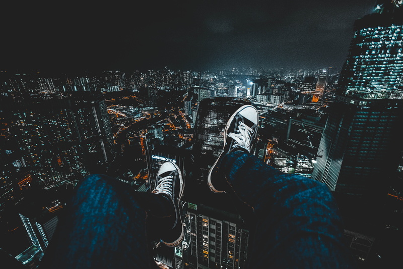 helicopter, lifestyles, architecture, person, modern, wearing, nighttime, blue, sneakers, men, city at night, outdoors, city, feet hanging down, built structure