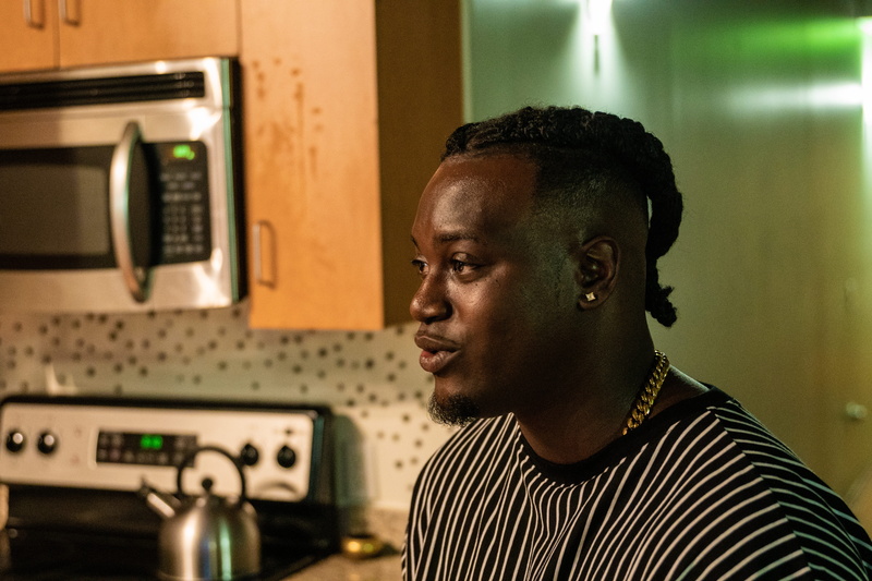 kitchen, afro hairstyle, appliance, microwave, focus on foreground, furniture, striped, closet, home interior, black, person, white, connection, close-up
