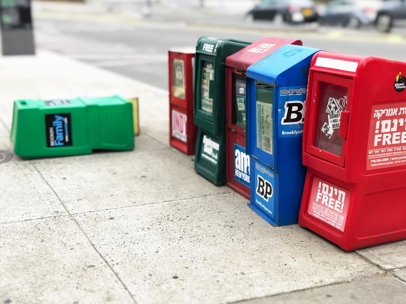 newspaper bins in line, pavement, 2K, over, down, focus on foreground, green color, western script, street, newspaper kiosk, city, city street with newspaper machine