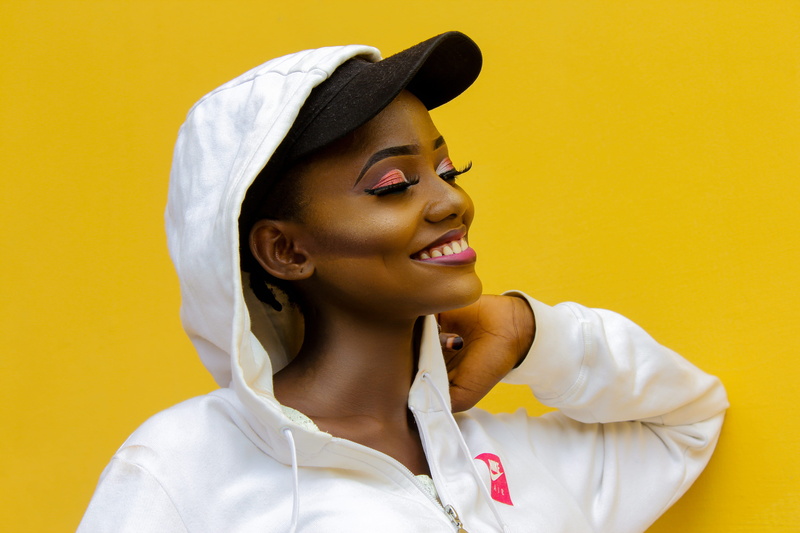 5K, closeup, closed, indoors, headshot, posing, front view, pretty, makeup, cap, relaxation, hoody sweater, wear, one person, yellow, clothing, colored background