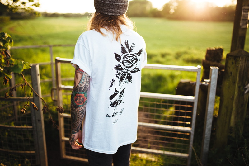 day, shirt, front, green color, sunlight, beanie, gate, field, leisure activity, clothing, one woman only, outside, rear view, rose, tattoo, plant, green