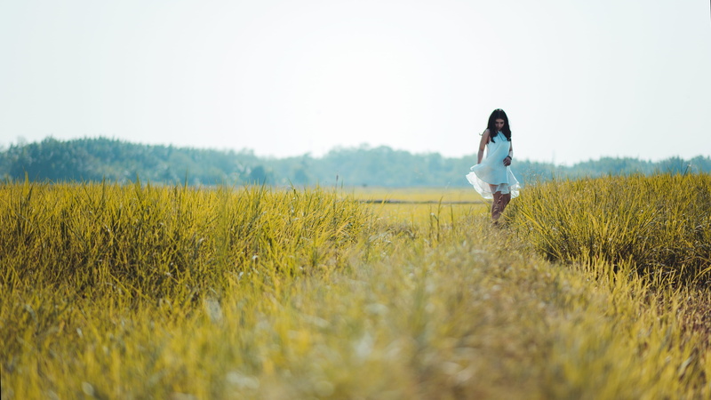 dress, grass, standing, young adult, farming, cropland, daylight, farm, fashion, green, farmland, one person, field, mountains, outdoors, nature, clouds