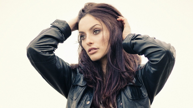 one person, leather, young adult, hand in hair, long hair, hairstyle, arms raised, leather jacket, beautiful woman, adult, looking at camera, brunette