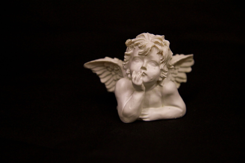 angel, black background, copy space, animal, cherub, statue, single object, figure, indoors, art, history, ceramic, emotion, animal wildlife, studio shot