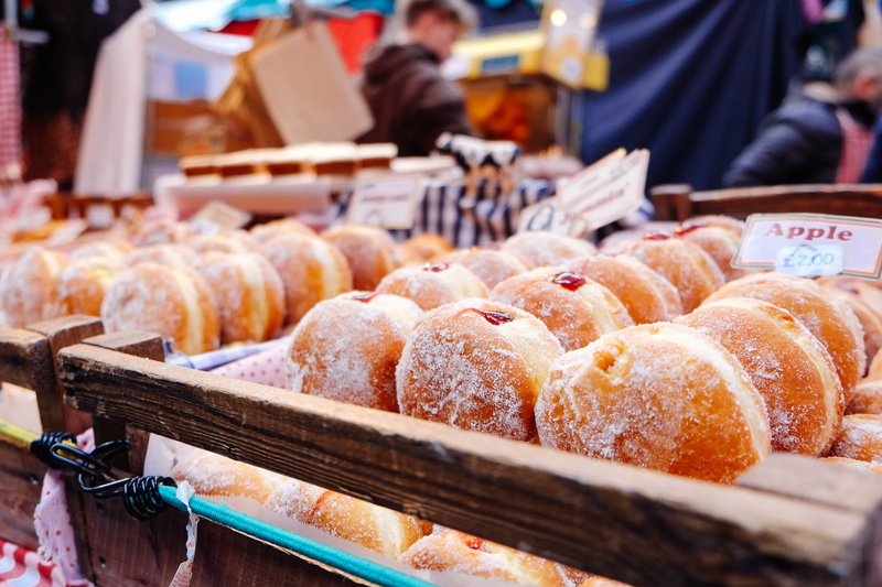 retail display, store, brown, fresh, outdoors, trays, photography, market stall, vendor, arrangement, near, market, incidental people, wearing, donut, focus on foreground