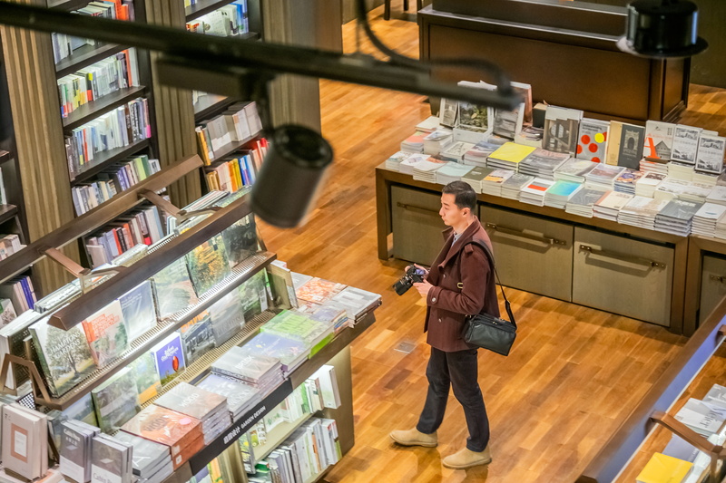 indoors, variation, decisions, hairstyle, flooring, apparel, holding, newsstand, person, black, wood, store, one person, full length, shop, library, standing