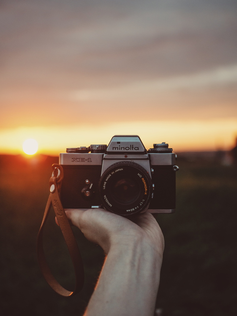 photographing, minolla, person, film, outdoors, classic, photographic equipment, hold, sky, human limb, holding, retro, lifestyles, activity, film camera