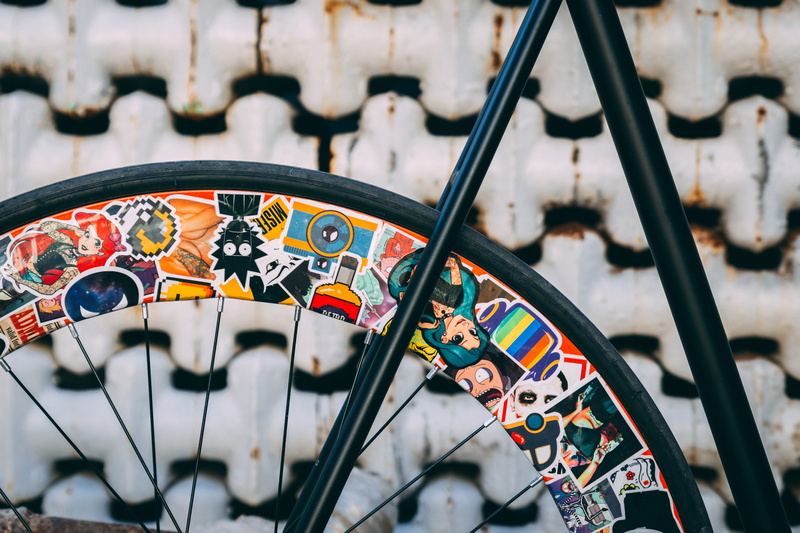 selective focus, amusement park, day, urban, stickerbomb, art, amusement park ride, city, accessories, focus on foreground, parked, wall, bike, wheel, clothing