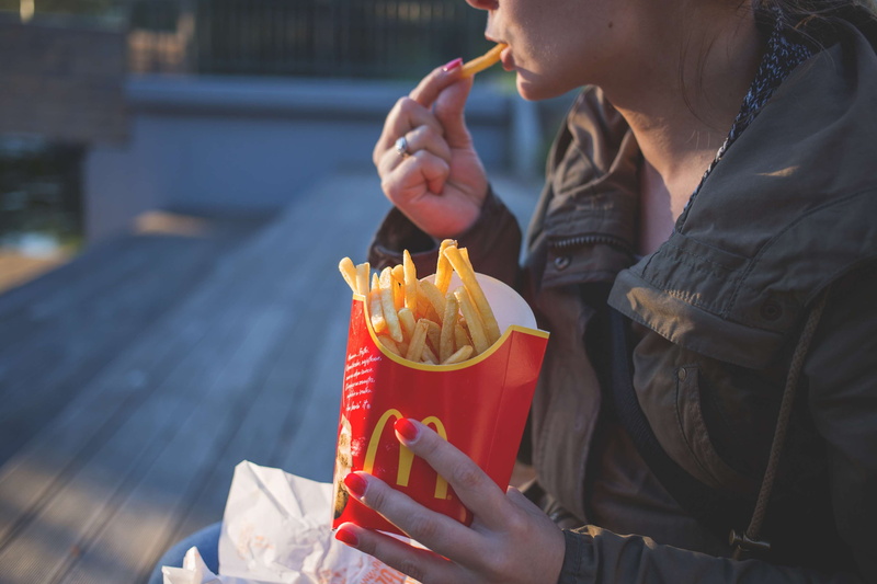 food, lady, coat, eating, focus on foreground, jacket, women, mcdonalds, one person, person, temptation, outdoors, nail polish, take out food, day, holding