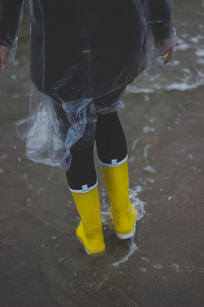 shoe, wearing, flood, wear, rubber boot, pavement, h2o, human body part, real people, low section, person, wet, one person, raincoat, yellow, body part