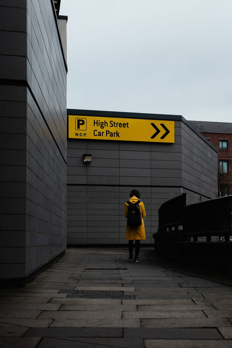 yellow, clothing, communication, built structure, lifestyles, wall - building feature, person, beside, transportation, walking, number, coat, men, building exterior