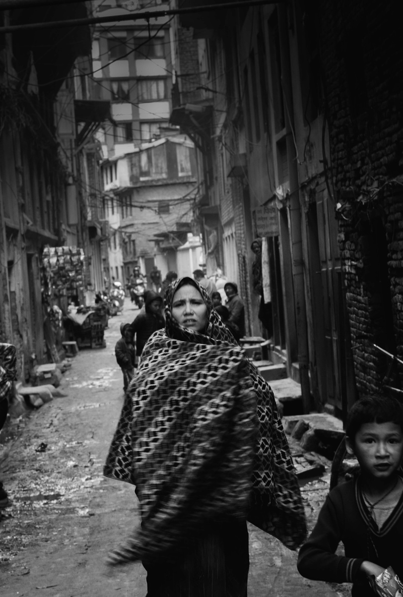 slum, human, coat, grayscale, warm clothing, leisure activity, fashion, road, cloak, women, overcoat, standing, group of people, building exterior, wearing