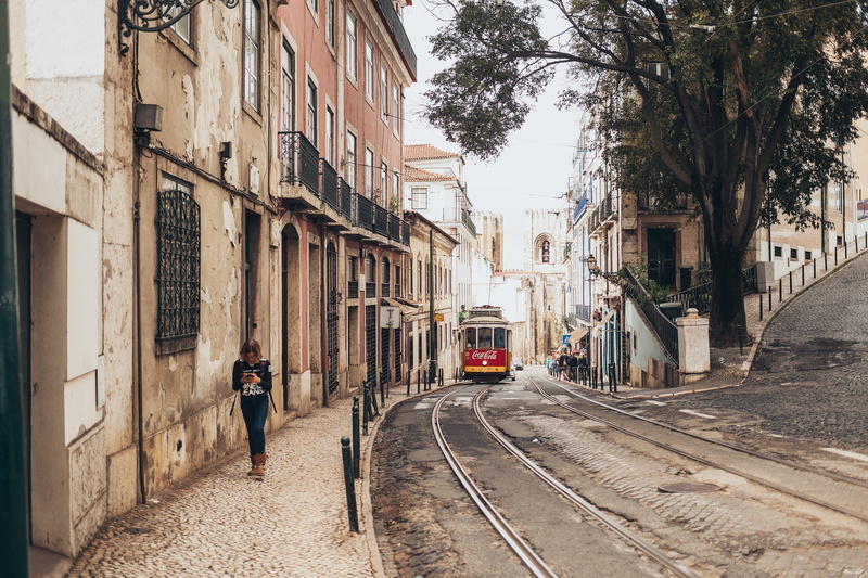 daytime, rail transportation, woman, tram, Tramway, railtrack, narrow, residential district, gothic, pavement, building, cobblestone, real people, building exterior