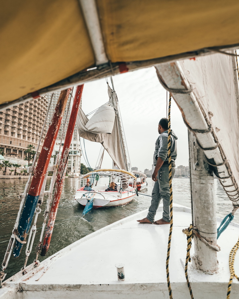 footwear, human, sea, sailboat, outdoors, architecture, day, side view, person, water, cairo, fisherman, shoe, building, apparel, boat, transportation