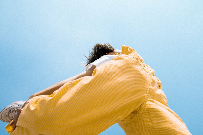 one person, yellow, judo, finger, wearing, young adult, nature, clothing, day, overcoat, grass, blue, clear sky, adult, lifestyles, martial arts, person