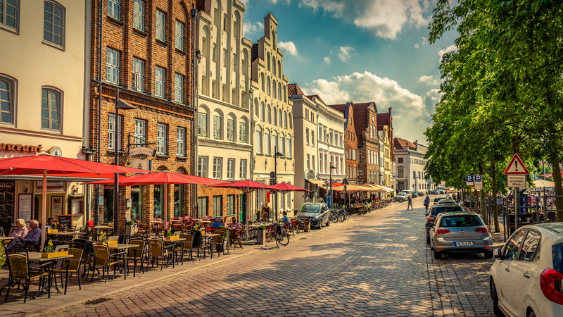motor vehicle, city, building exterior, facade, land vehicle, sky, window, chairs, houses, building, street, architecture, lübeck, light, table, mode of transportation